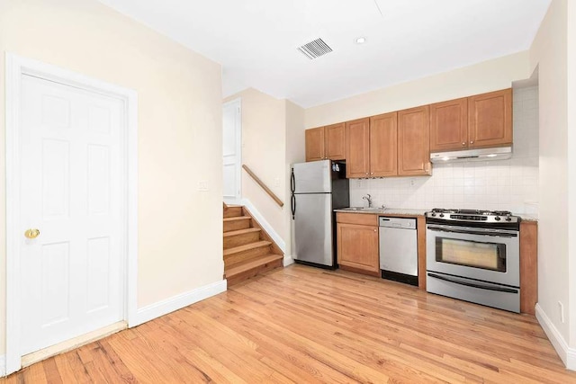 59 E 73rd St, New York City, NY 10021 - kitchen with stainless steel appliances, under cabinet range hood, light wood-type flooring, and decorative backsplash