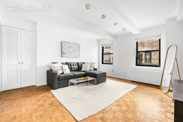 living area featuring baseboards and beamed ceiling