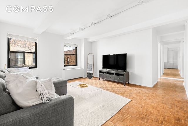 living area with radiator, baseboards, and beam ceiling