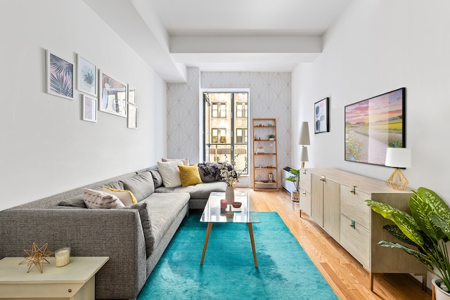 living area with wallpapered walls, light wood-style flooring, and an accent wall