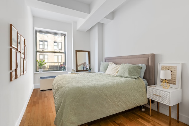 bedroom featuring radiator, wood finished floors, and baseboards