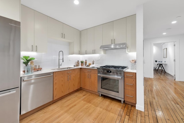 554 Broome St Unit 4Thfloor, New York City, NY 10013 - kitchen featuring appliances with stainless steel finishes, a sink, under cabinet range hood, light wood finished floors, and light countertops