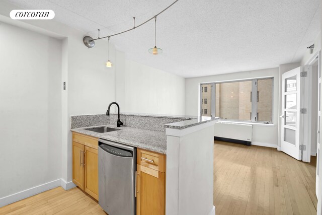 kitchen with dishwasher, a sink, a peninsula, light wood finished floors, and light stone countertops