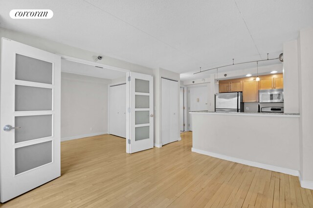 unfurnished living room with light wood-style flooring and baseboards
