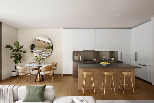 kitchen featuring a kitchen island, a breakfast bar area, modern cabinets, dark countertops, and wood finished floors