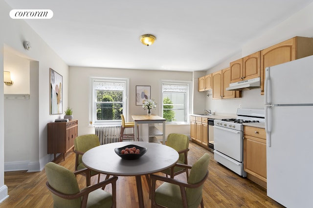 kitchen featuring white appliances, light countertops, dark wood-type flooring, under cabinet range hood, and visible vents