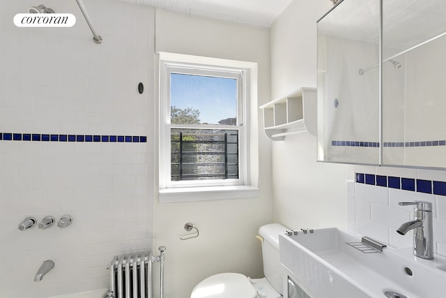 bathroom with toilet, a sink, washtub / shower combination, and radiator heating unit