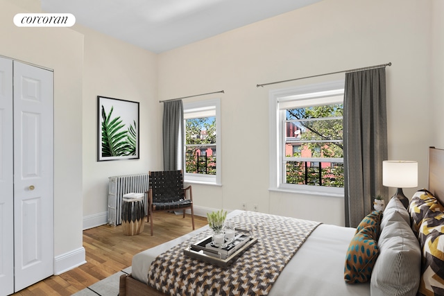bedroom with baseboards, radiator heating unit, and wood finished floors