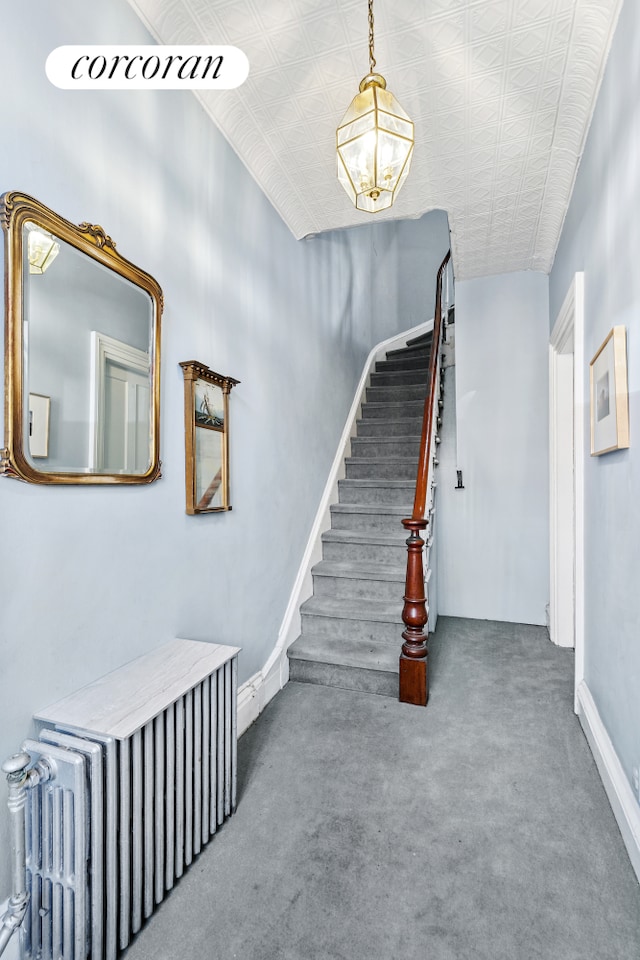 stairs featuring an inviting chandelier, carpet flooring, an ornate ceiling, and radiator heating unit