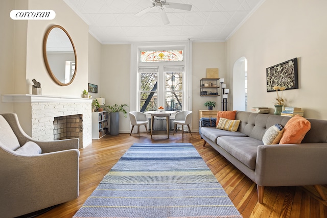 living room with ornamental molding, a ceiling fan, arched walkways, and wood finished floors
