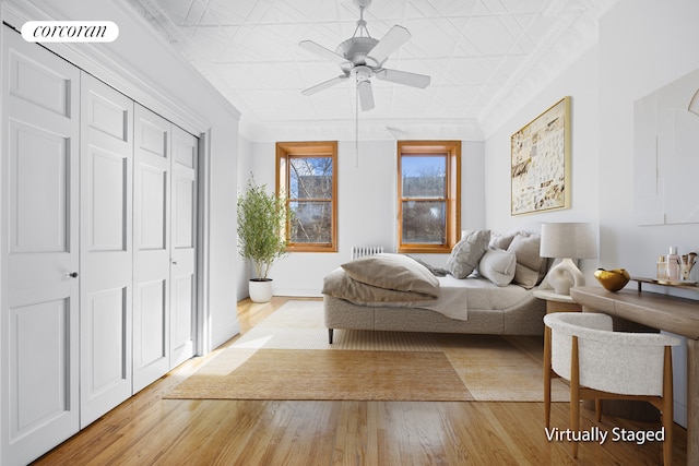 bedroom featuring a closet, visible vents, light wood finished floors, baseboards, and an ornate ceiling