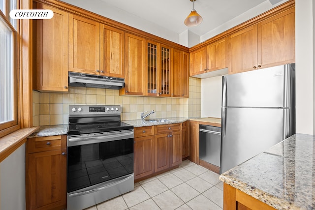 kitchen with under cabinet range hood, a sink, brown cabinetry, and appliances with stainless steel finishes