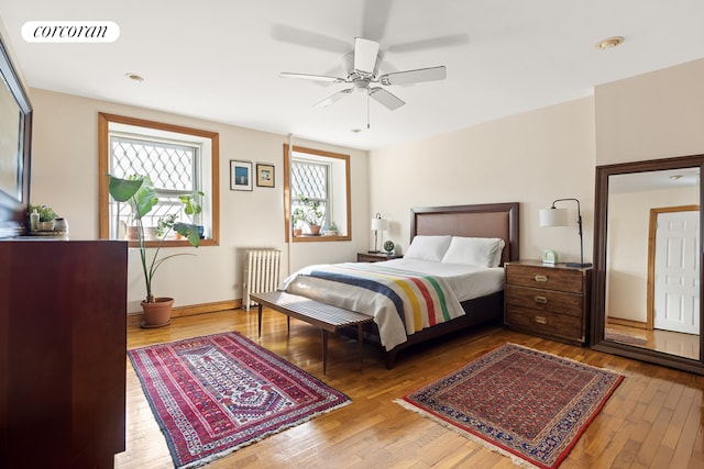 bedroom featuring visible vents, baseboards, ceiling fan, hardwood / wood-style flooring, and radiator heating unit