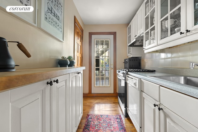 kitchen featuring glass insert cabinets, light wood-style flooring, light countertops, white cabinetry, and white dishwasher