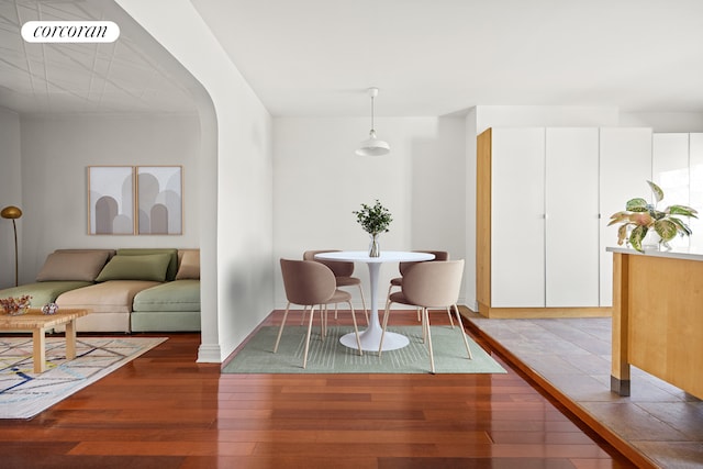 dining space with hardwood / wood-style floors, baseboards, visible vents, and arched walkways