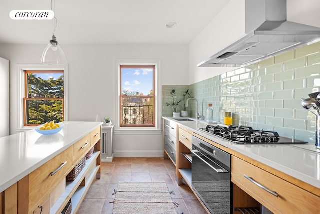 kitchen featuring wall chimney exhaust hood, modern cabinets, visible vents, a sink, and oven