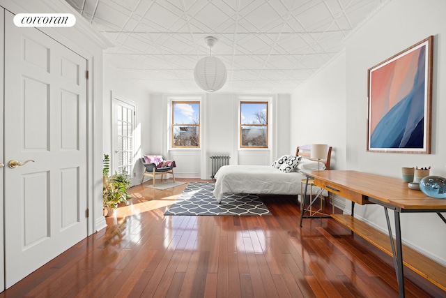 bedroom with baseboards, dark wood-style floors, visible vents, an ornate ceiling, and radiator