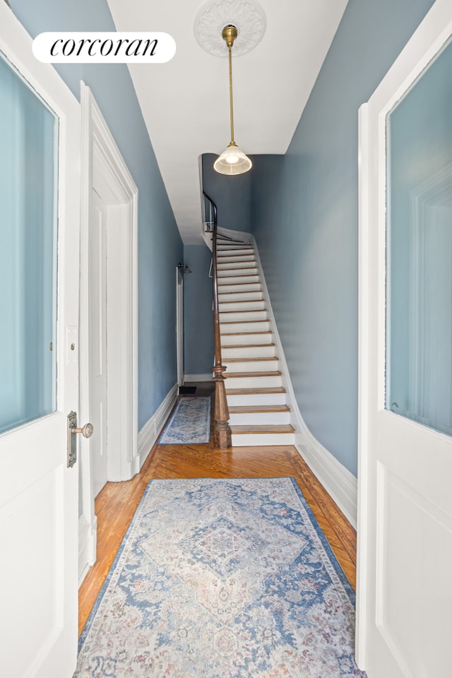 entryway with wood finished floors, baseboards, and stairs