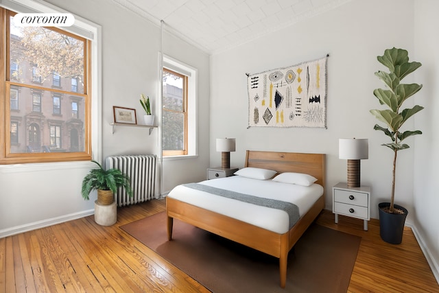 bedroom featuring radiator heating unit, hardwood / wood-style flooring, and baseboards