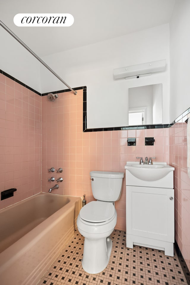 full bathroom with toilet, tile walls, vanity, tile patterned floors, and bathing tub / shower combination