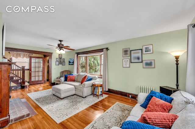 living room featuring baseboards, radiator, ceiling fan, and wood finished floors
