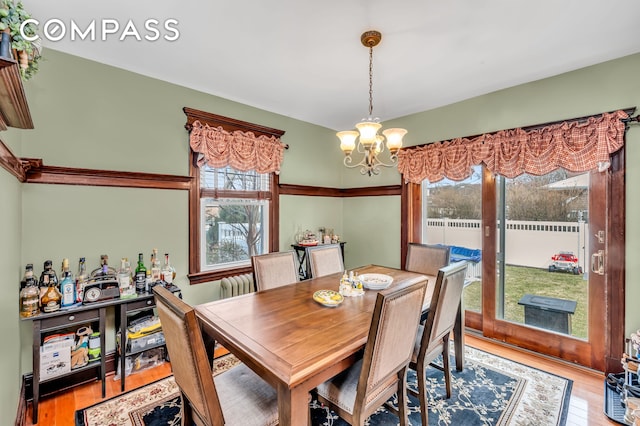 dining space with an inviting chandelier, wood finished floors, and a healthy amount of sunlight