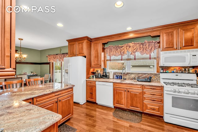 kitchen featuring white appliances, light stone countertops, plenty of natural light, and a sink