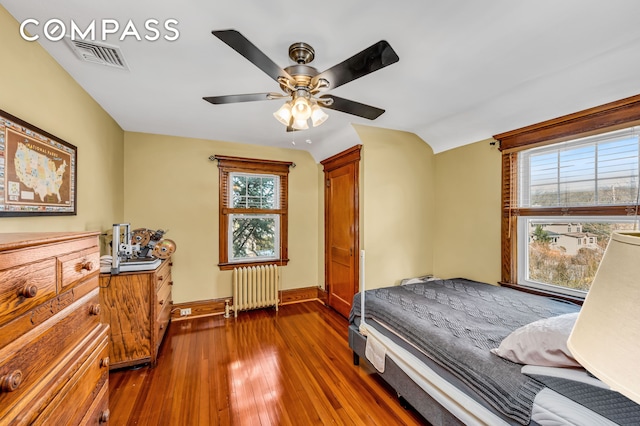 bedroom with visible vents, baseboards, ceiling fan, radiator heating unit, and dark wood-type flooring