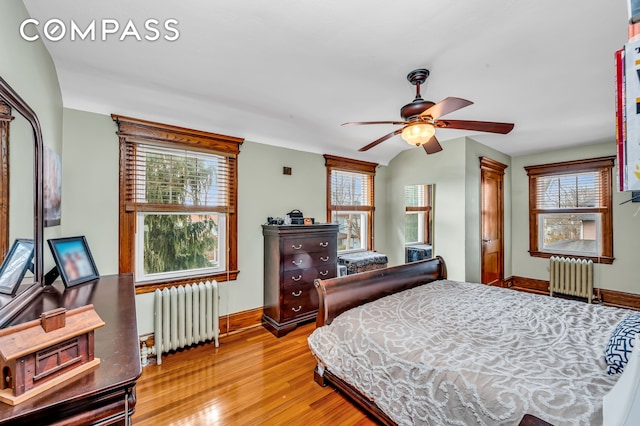bedroom featuring baseboards, radiator heating unit, and light wood-type flooring