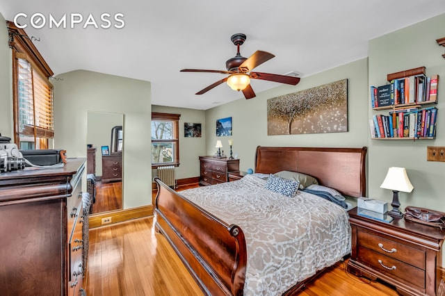 bedroom featuring a ceiling fan, light wood-style flooring, and radiator heating unit