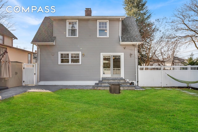 rear view of property featuring a gate, fence, a yard, and a chimney
