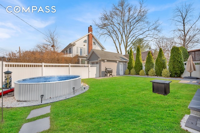 view of yard with a swimming pool, fence, and an outbuilding