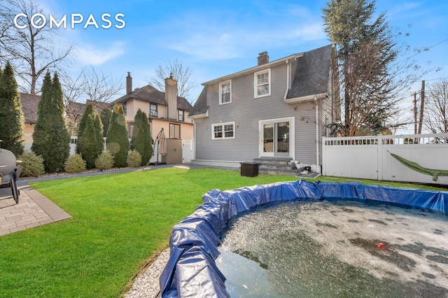 back of property featuring a yard, fence, a chimney, and a patio area