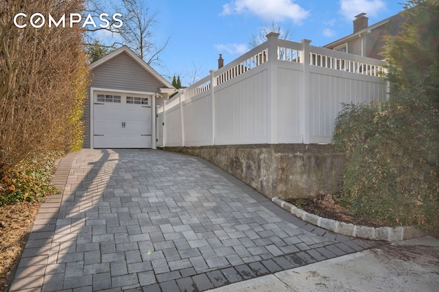 view of side of home featuring fence and decorative driveway