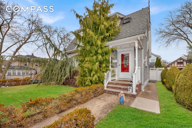 view of front of property with fence, a shingled roof, and a front yard