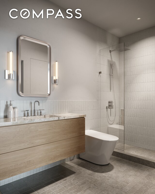 bathroom with tile walls, wainscoting, a walk in shower, vanity, and toilet