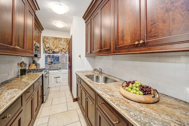 kitchen featuring appliances with stainless steel finishes, a sink, tasteful backsplash, and light stone countertops