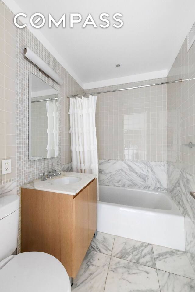 255 E 74th St Unit 14C, New York City, NY 10021 - full bathroom with toilet, vanity, tile walls, shower / bath combo with shower curtain, and marble look tile flooring