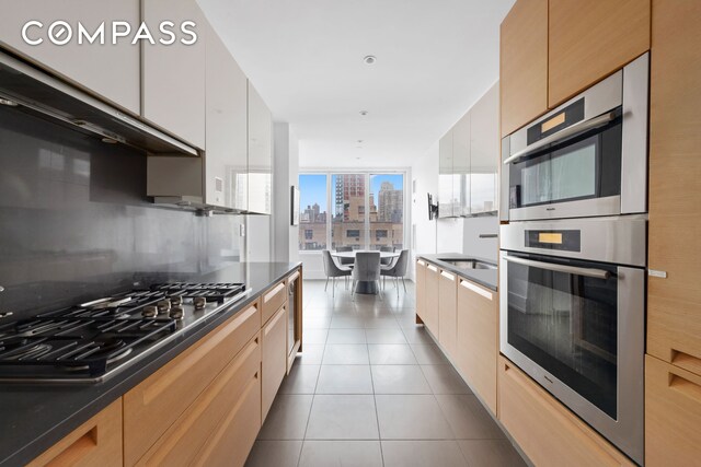 255 E 74th St Unit 14C, New York City, NY 10021 - kitchen with stainless steel appliances, a city view, dark countertops, tile patterned flooring, and modern cabinets
