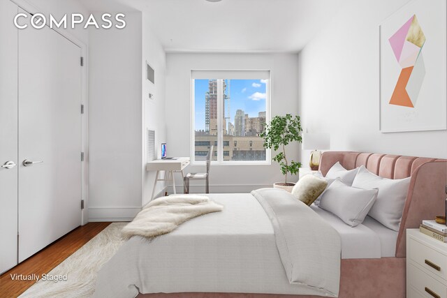 255 E 74th St Unit 14C, New York City, NY 10021 - bedroom featuring wood finished floors, a view of skyline, and baseboards