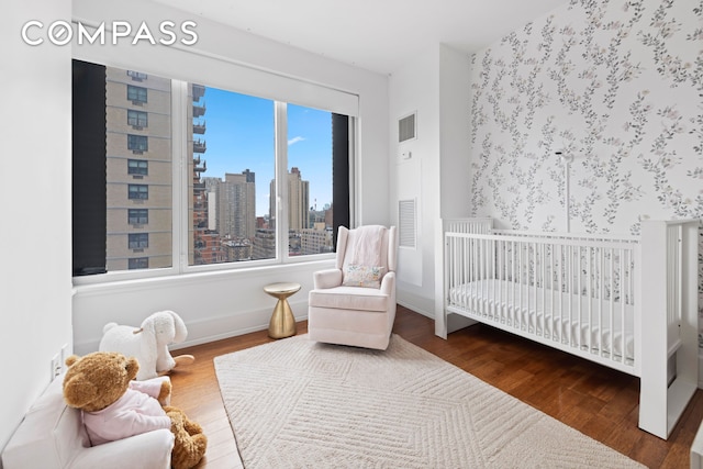 bedroom with wood finished floors, a view of skyline, a nursery area, and baseboards