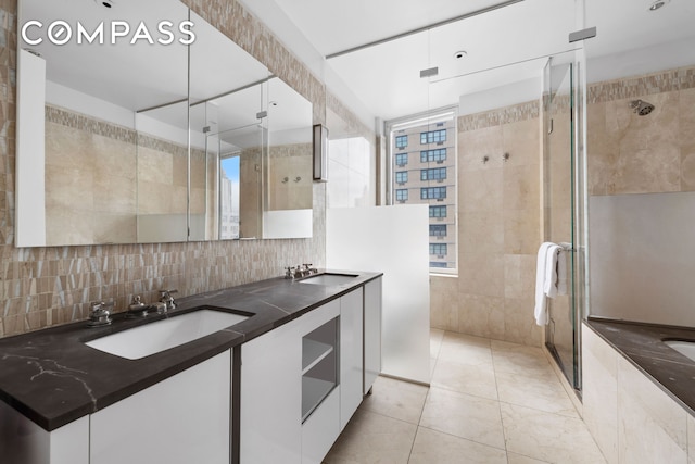 bathroom with tile walls, a stall shower, double vanity, and backsplash