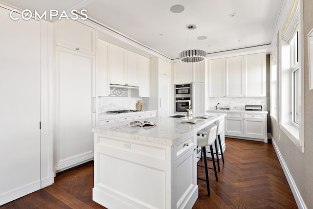 2 Park Pl Unit 35A, New York City, NY 10007 - kitchen featuring a breakfast bar area, white cabinets, decorative backsplash, and a center island with sink