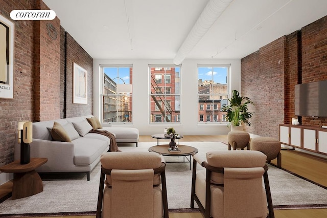 living area with brick wall and wood finished floors