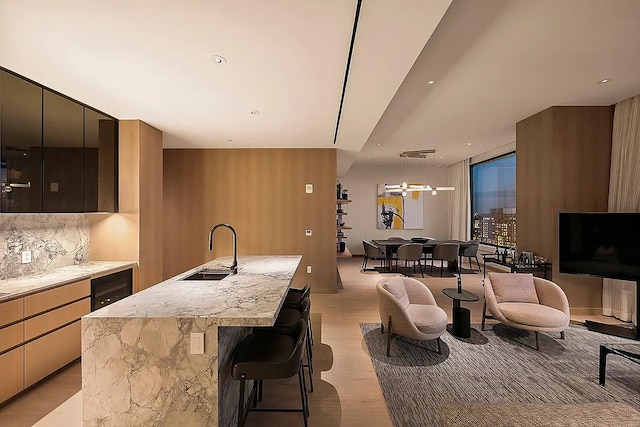 kitchen with tasteful backsplash, a sink, a kitchen island with sink, a breakfast bar, and modern cabinets