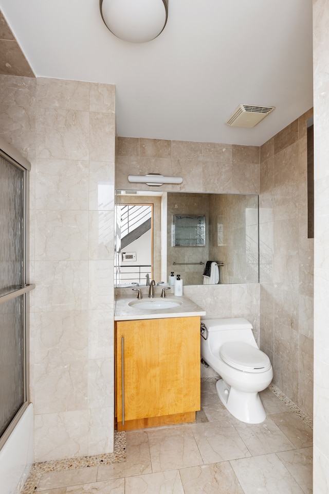 bathroom with tile walls, toilet, marble finish floors, and vanity