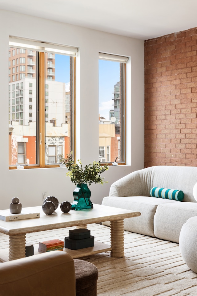 living area featuring brick wall and plenty of natural light