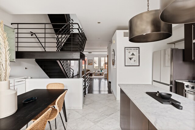 kitchen featuring freestanding refrigerator, recessed lighting, and light marble finish flooring