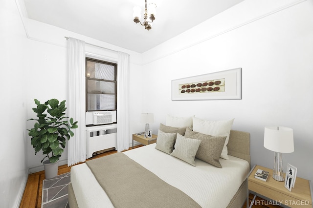 bedroom with radiator, cooling unit, and wood finished floors
