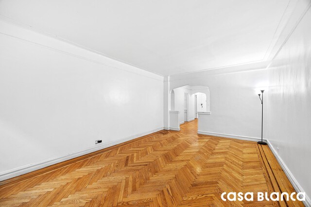 spare room featuring arched walkways and baseboards
